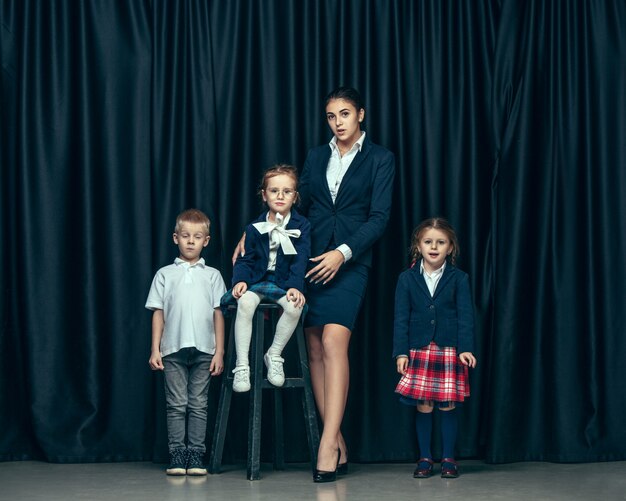 Cute stylish children on dark  space. The beautiful teen girls and boy standing together