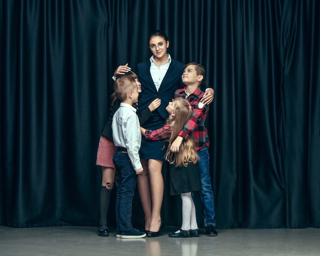 Free photo cute stylish children on dark studio background. the beautiful teen girls and boy standing together