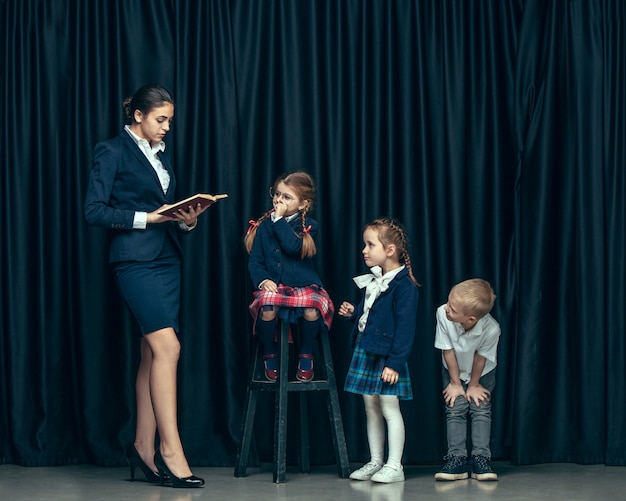 Cute stylish children on dark studio. The beautiful teen girls and boy standing together