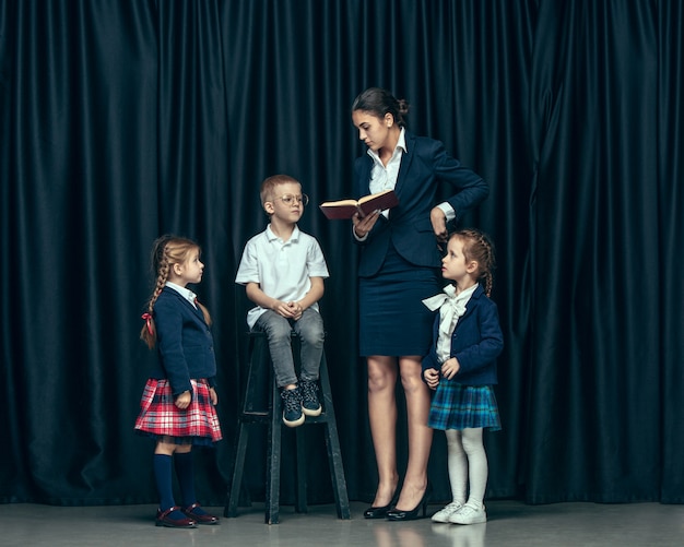 Cute stylish children on dark studio. The beautiful teen girls and boy standing together