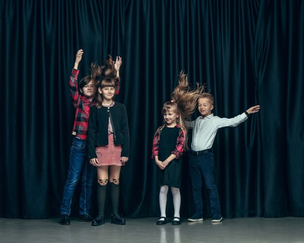 Cute stylish children on dark studio. The beautiful teen girls and boy standing together