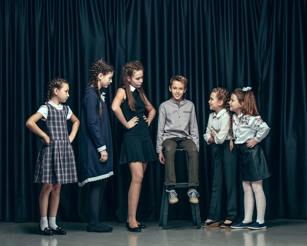 Cute stylish children on dark studio. beautiful teen girls and boy standing together