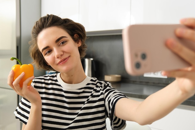 Free photo cute and stylish lifestyle blogger young woman taking selfie with fresh pepper eating healthy