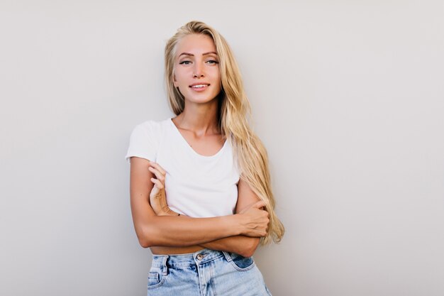 Cute tanned woman with blue eyes posing in studio. Indoor photo of pleasant long-haired woman