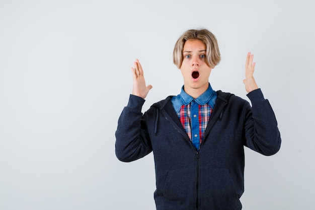 Cute teen boy in shirt, hoodie showing large size sign and looking wondered , front view.