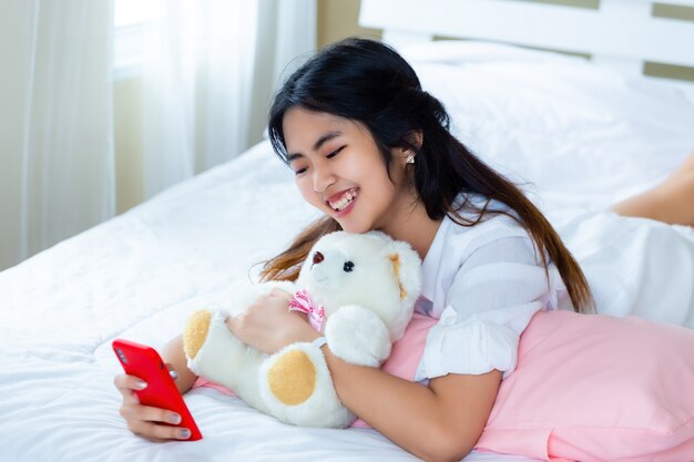 Cute teenage female joyful with smartphone on bed