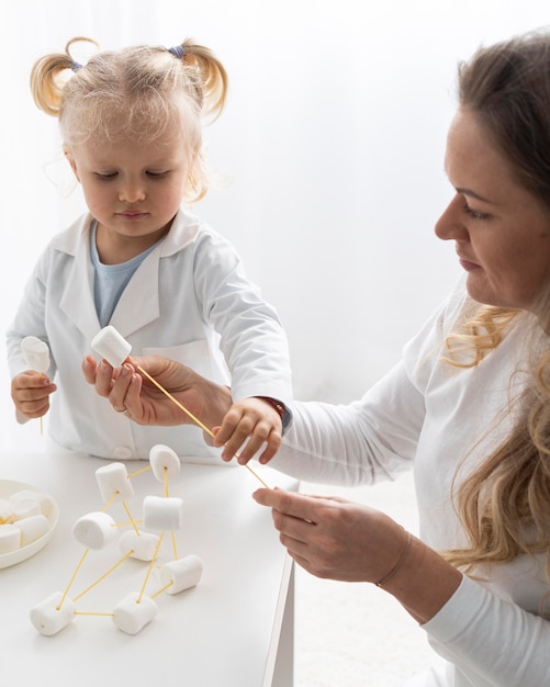 Free photo cute toddler and woman learning about science with marshmallows and pasta