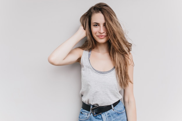 Free photo cute white girl playing with her long hair and looking. indoor shot of interested caucasian lady spending time