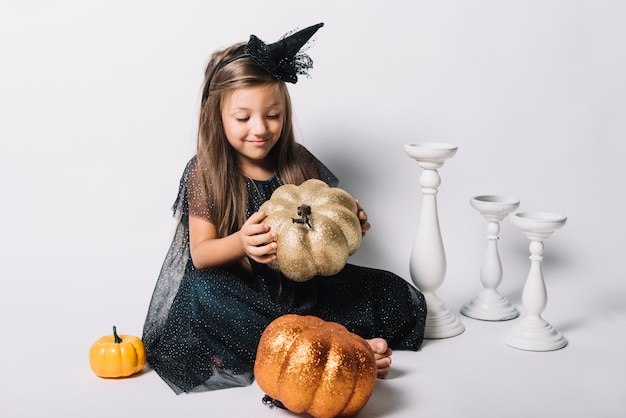 Free photo cute witch playing with pumpkins