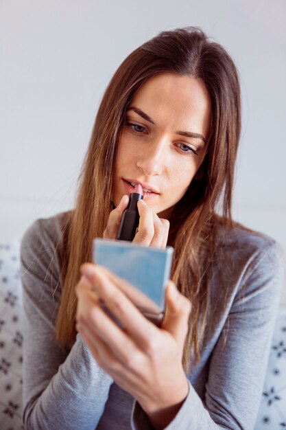 Cute woman applying lipstick