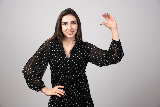 Cute woman in black dress showing open space.