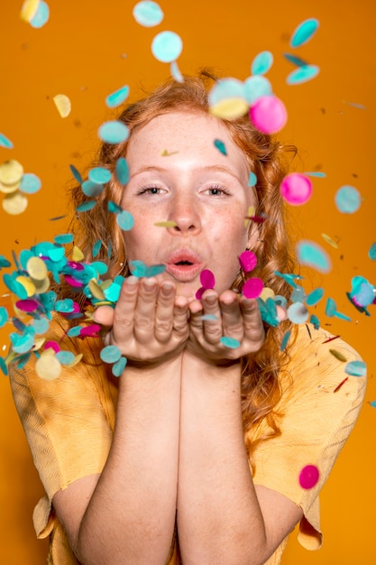 Free photo cute woman blowing confetti