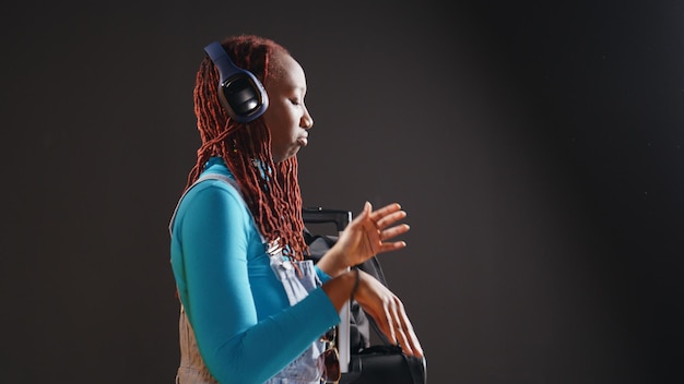 Free photo cute woman doing heart shaped symbol, listening to music and showing romantic sing in studio. cheerful traveller expressing feelings and romance gesture, having fun on camera. handheld shot.