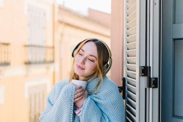 Cute woman enjoying music on balcony