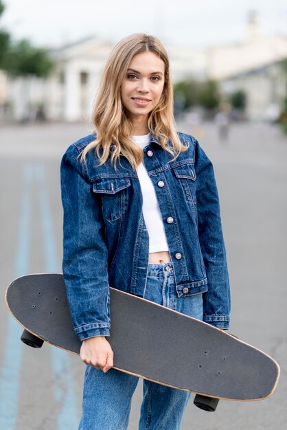 Cute woman holding a skateboard front view