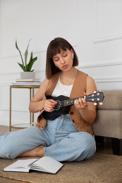 Cute woman playing the ukulele at home