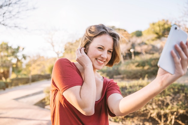 Free photo cute woman taking selfie in park