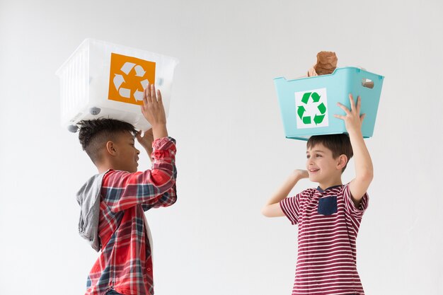 Cute young boys holding recycling boxes