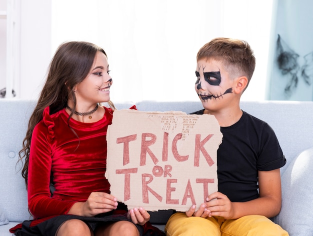 Free photo cute young brothers holding trick or treat sign