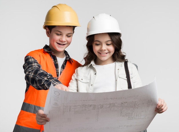 Free photo cute young girl and boy reading construction plan