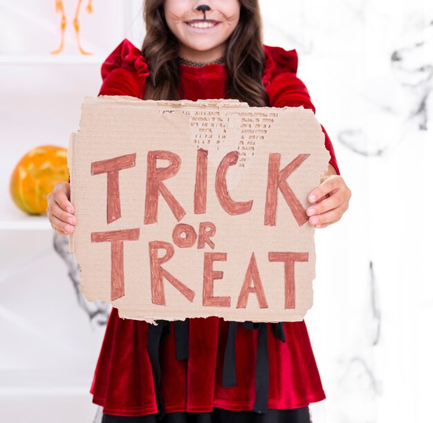 Cute young girl holding trick or treat sign