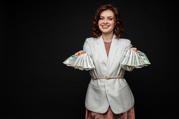 Cute young girl shows a lot of money in the hands, picture isolated on black space