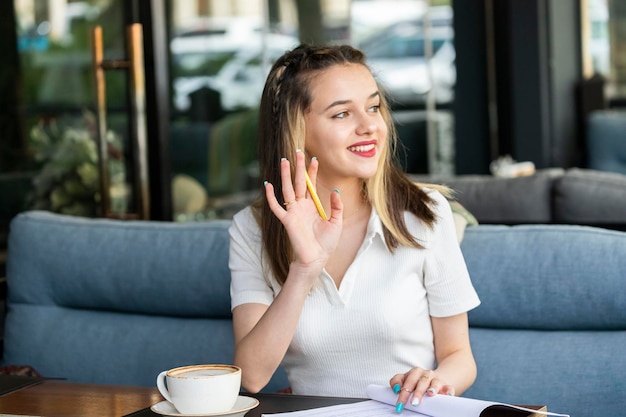 Cute young girl sitting at the restaurant and shaking her hand aside