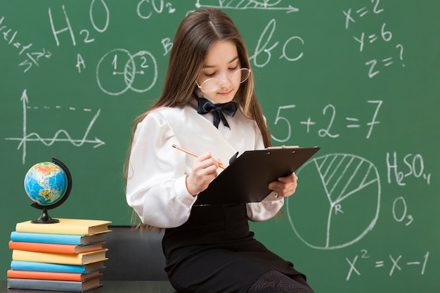 Cute young girl writing in clipboard