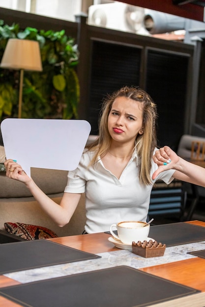 Cute young lady holding idea board and gesture thumb down