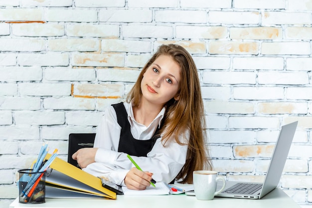 Cute young student sitting on white background and looking at the objective High quality photo