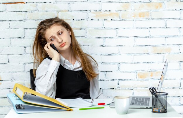 Cute young student sitting on white background and talking on the phone High quality photo