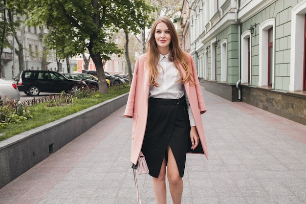 Free photo cute young stylish beautiful woman walking in street, wearing pink coat, purse, white shirt, black skirt, fashion outfit, autumn trend, smiling happy, accessories