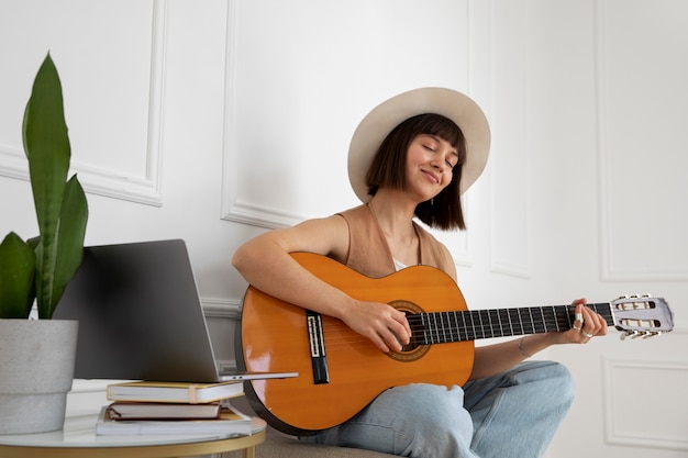 Cute young woman playing guitar indoors