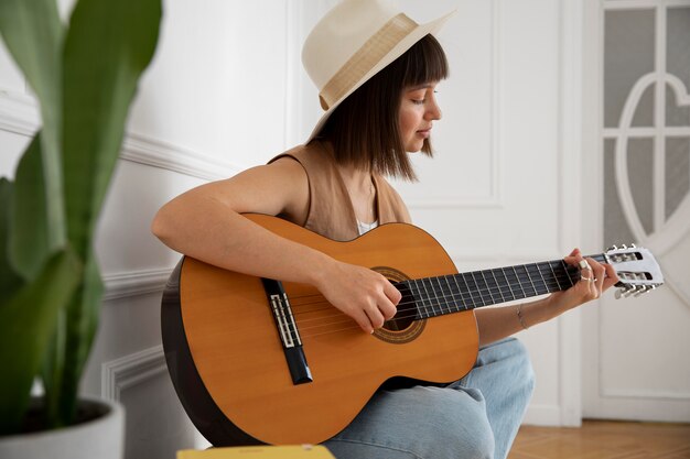 Cute young woman playing guitar indoors