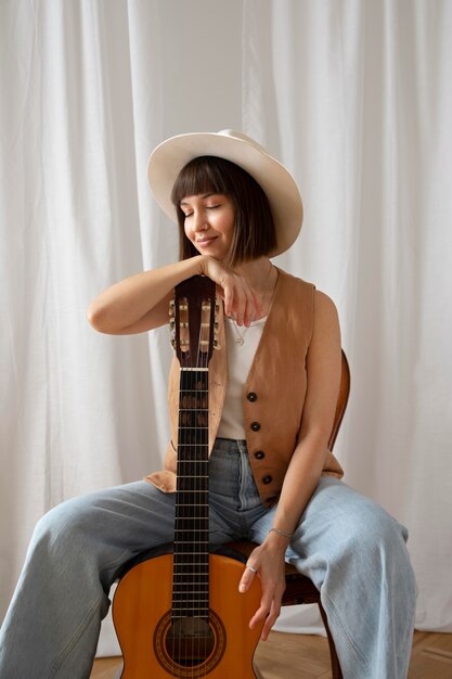 Cute young woman posing with a guitar indoors