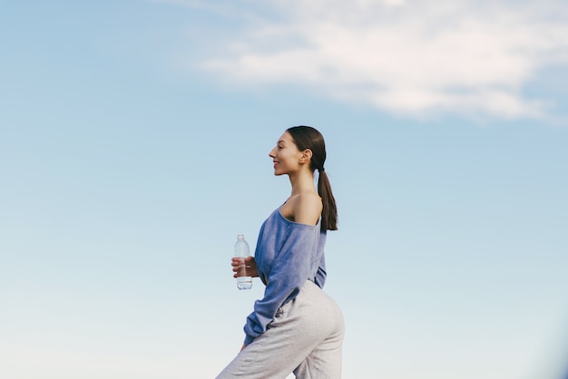 Cute young woman training with bottle of water