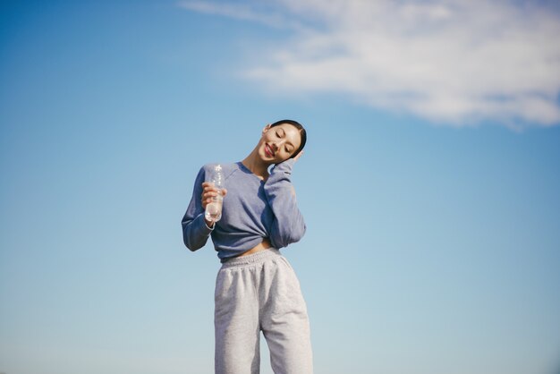 Cute young woman training with bottle of water