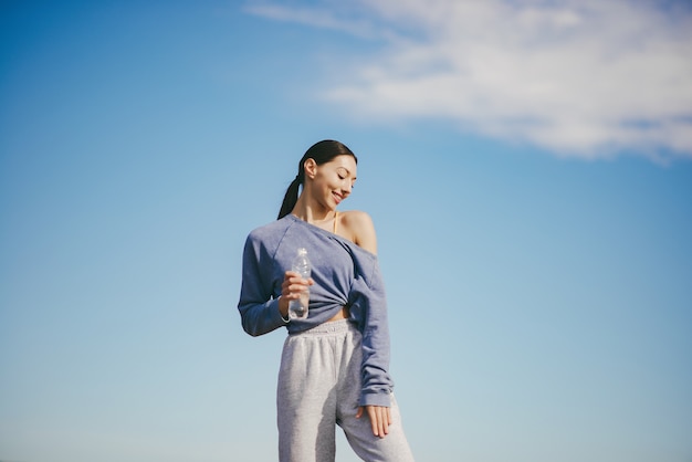 Cute young woman training with bottle of water