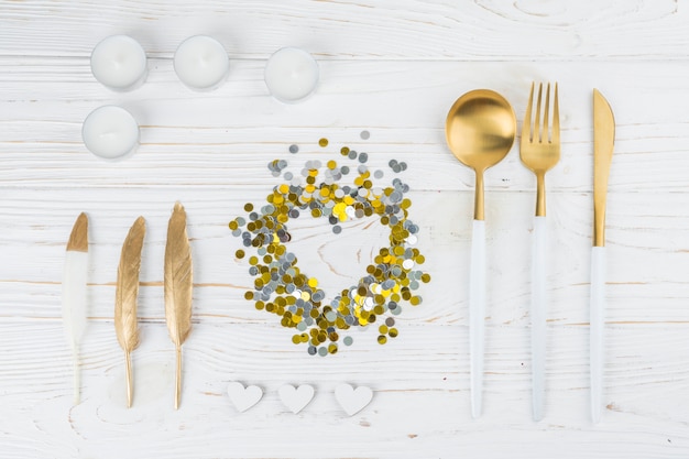 Cutlery near ornament glitters, feathers and candles