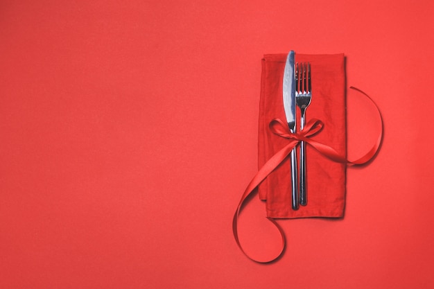 Free Photo cutlery tied with a red bow on a red napkin