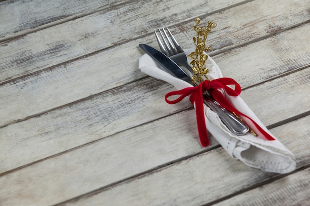 Free photo cutlery wrapped with christmas motif on a wooden table