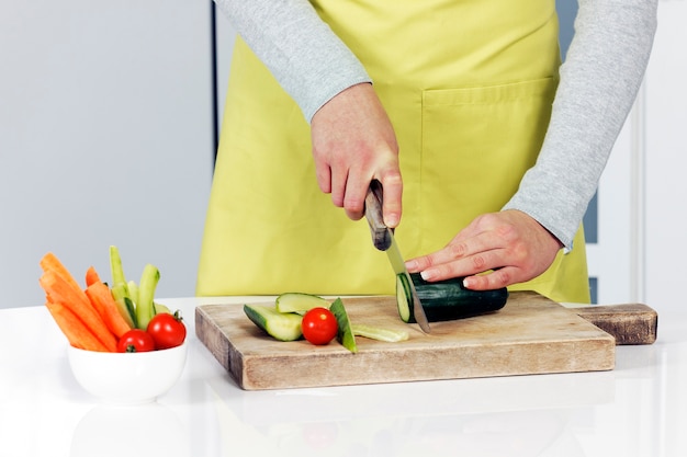 Free photo cutting cucumber and vegetables on background