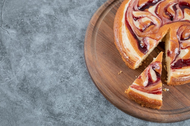 Cutting a slice of strawberry pie on wooden board.