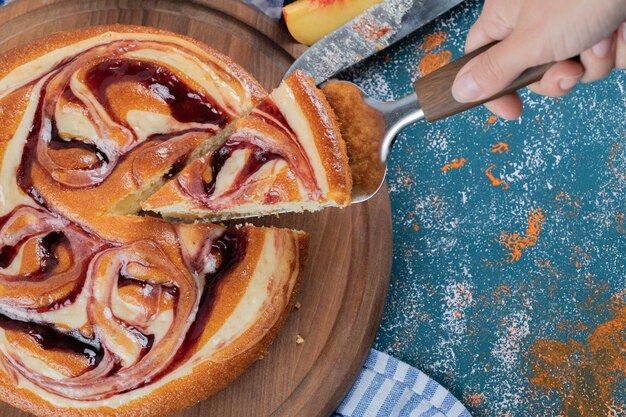 Cutting a slice of strawberry pie on wooden board.