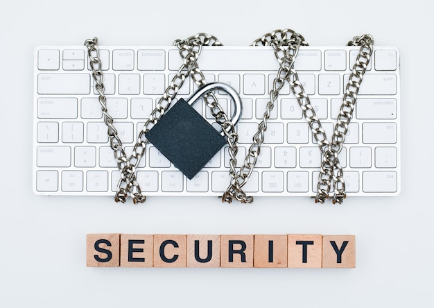 Free Photo cyber safety concept with chain and padlock on keyboard, wooden cubes on white background flat lay.