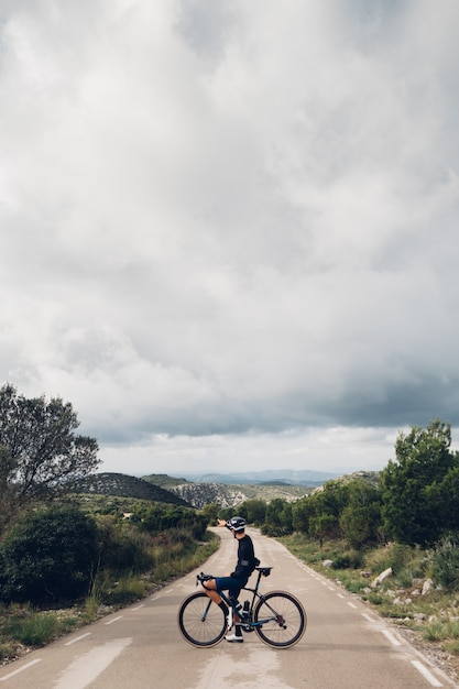 Free photo cyclist riding a bike at sunset in a mountain road