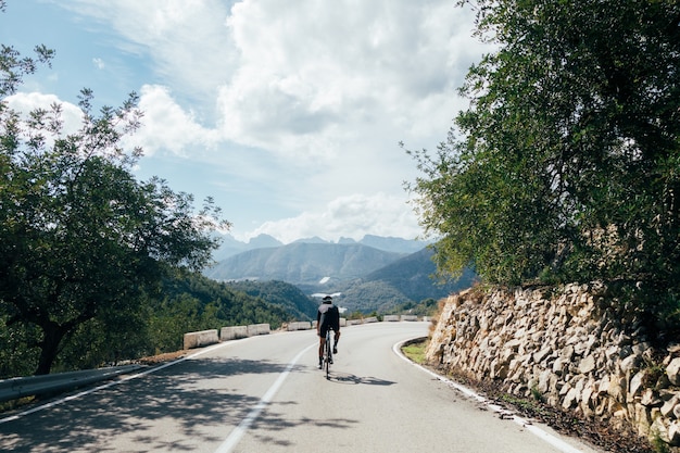 Cyclist riding a bike at sunset in a mountain road