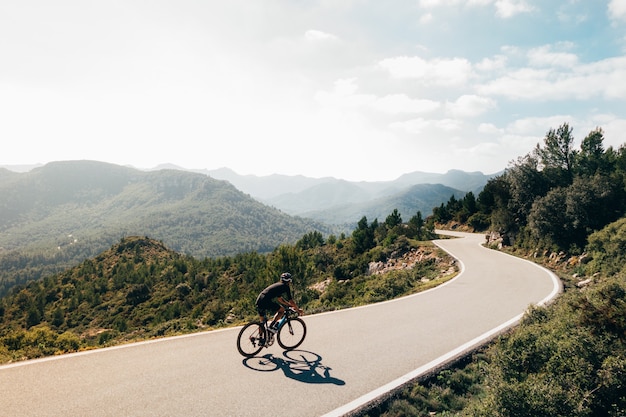 Free photo cyclist riding a bike at sunset in a mountain road