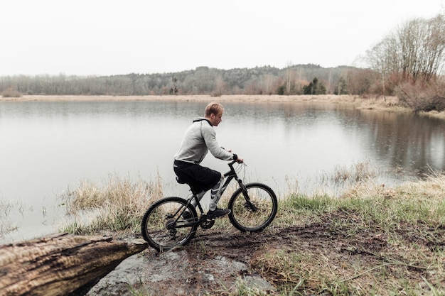 Free photo cyclist riding his mountain bike near the idyllic lake