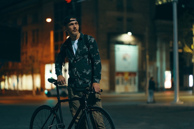 Free photo cyclists standing on the road aside his classic bike while watch